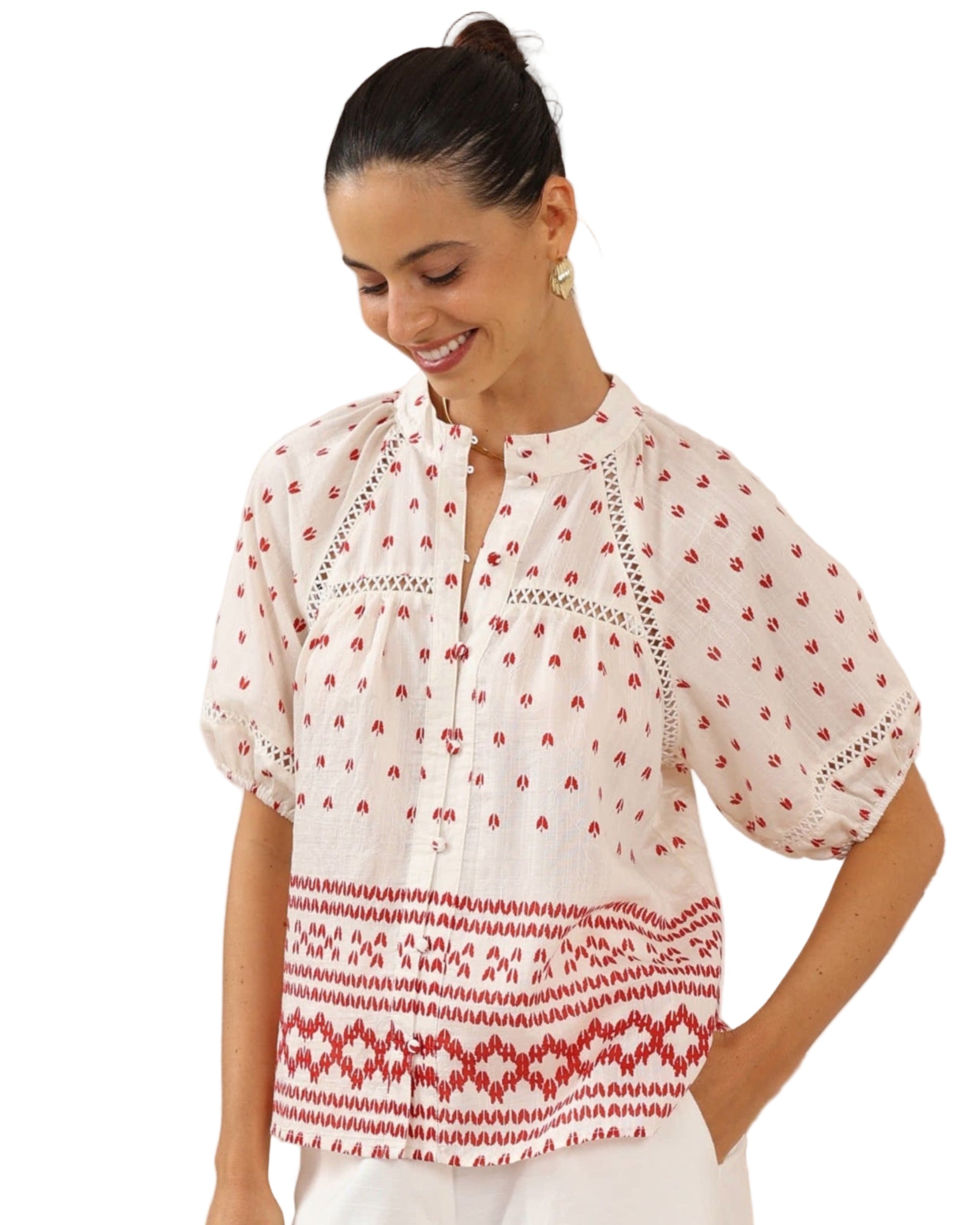 Woman wearing a white blouse with red patterns in a minimalistic setting