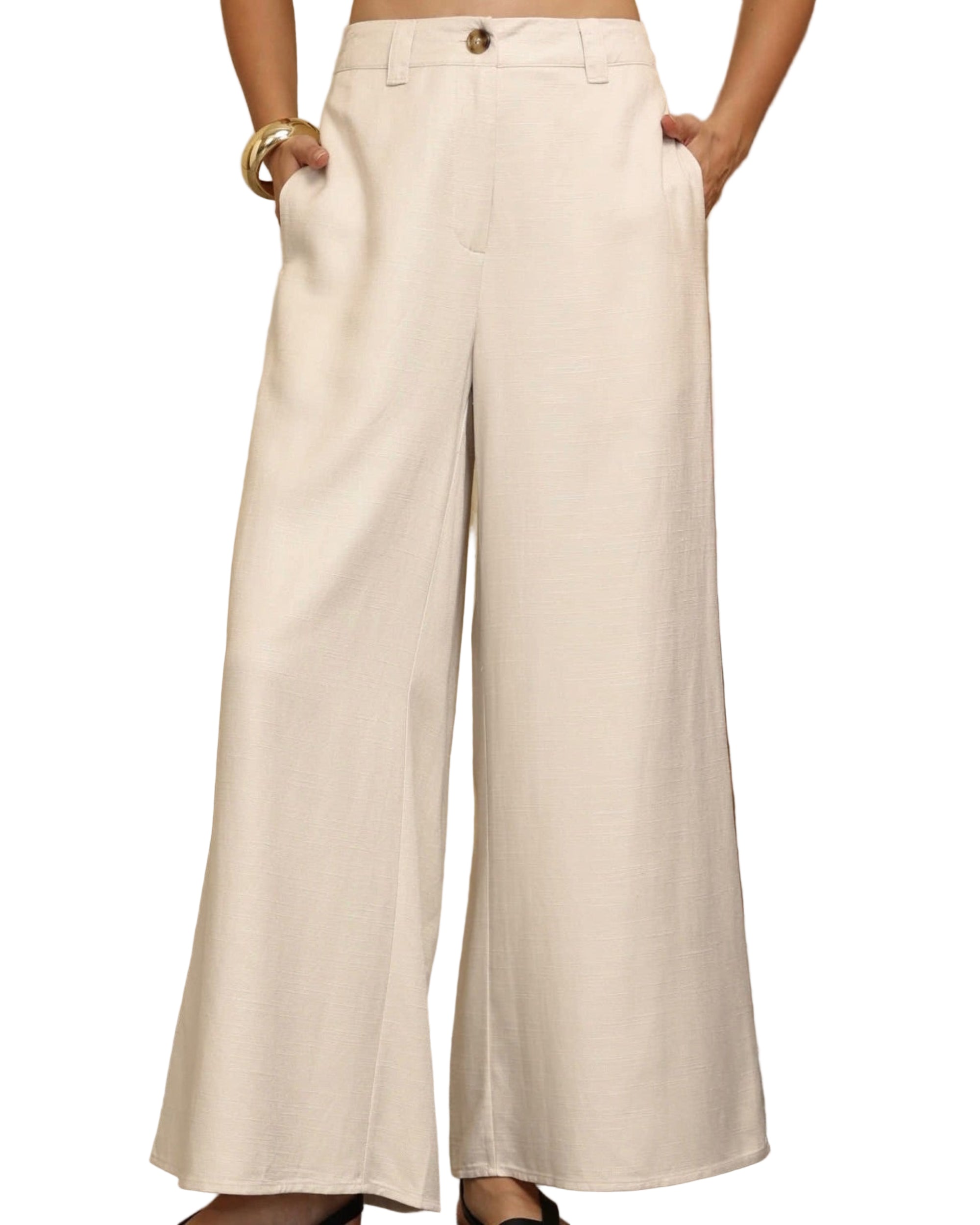 Person wearing white wide-leg pants standing in a room with wooden furniture and decor.