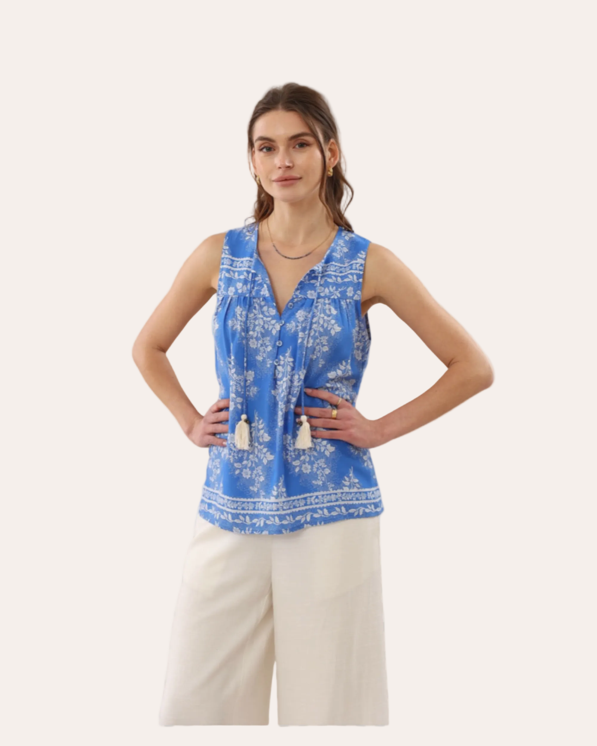 Woman wearing a blue patterned top and beige pants on a transparent background