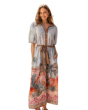 Woman in a patterned dress walking through a narrow street with wooden walls.