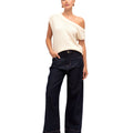 Woman wearing a white sleeveless top and dark blue jeans on a white background