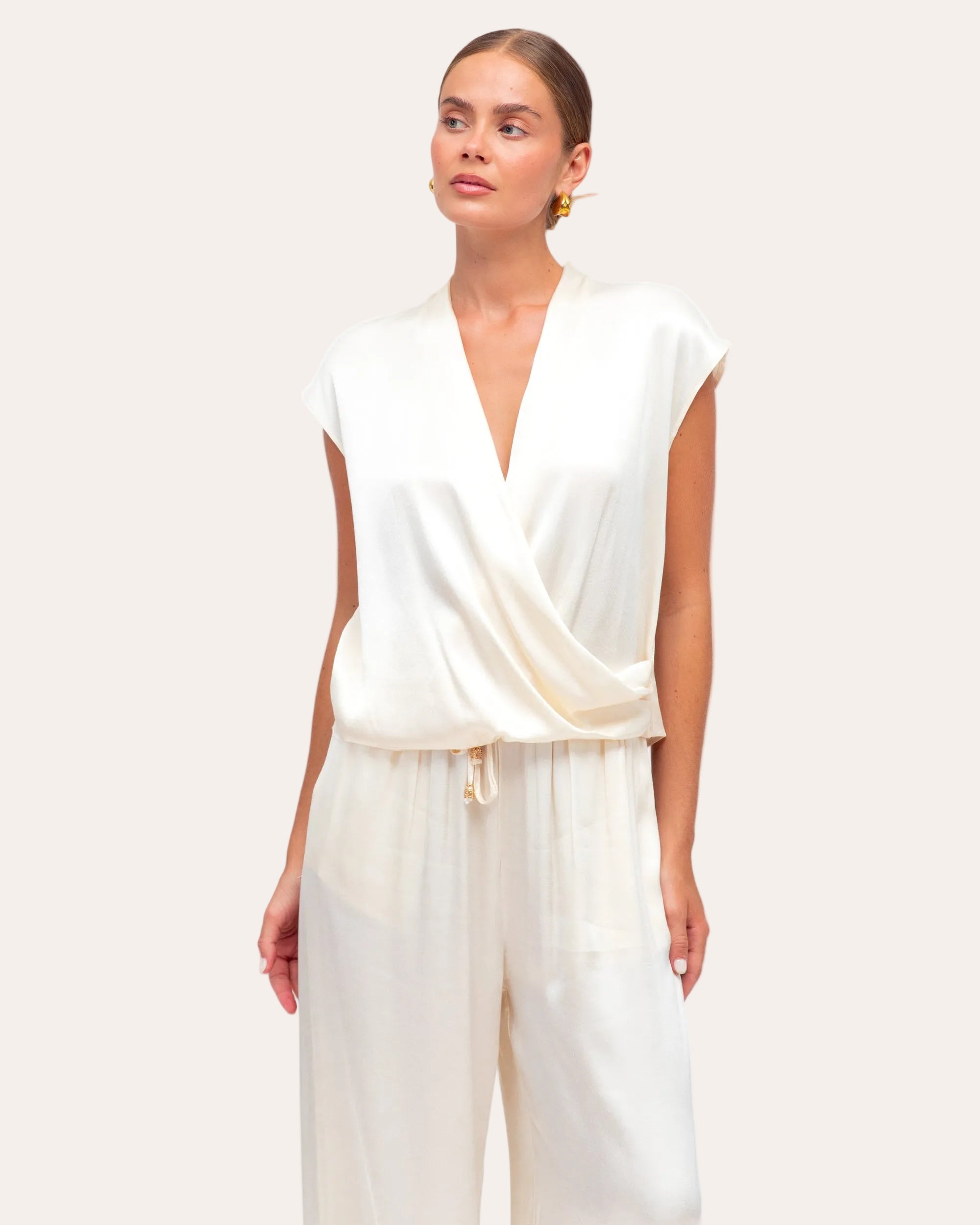 Woman wearing a white jumpsuit on a plain background