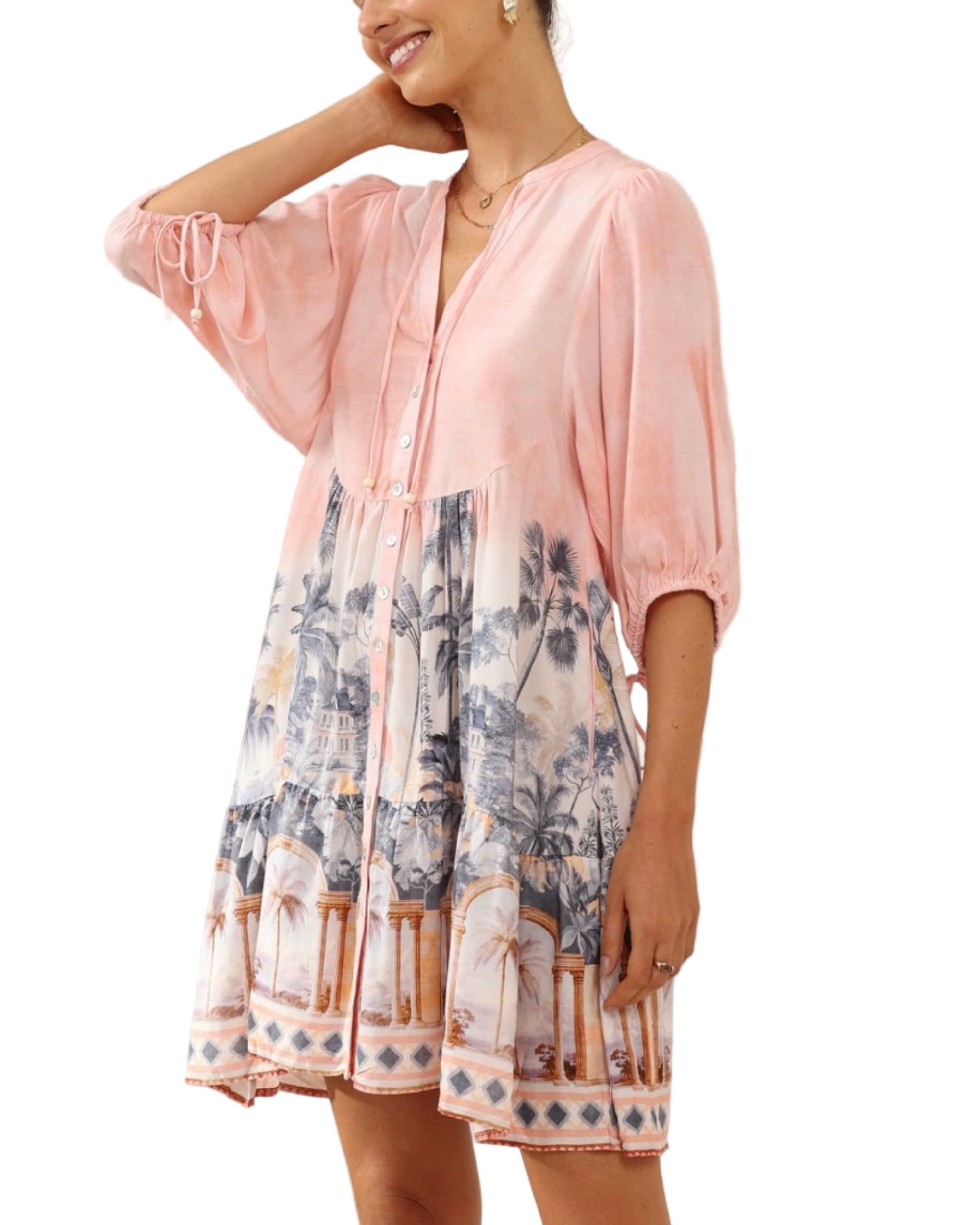 Woman wearing a pink kimono-style garment with a floral pattern in a minimalistic setting.