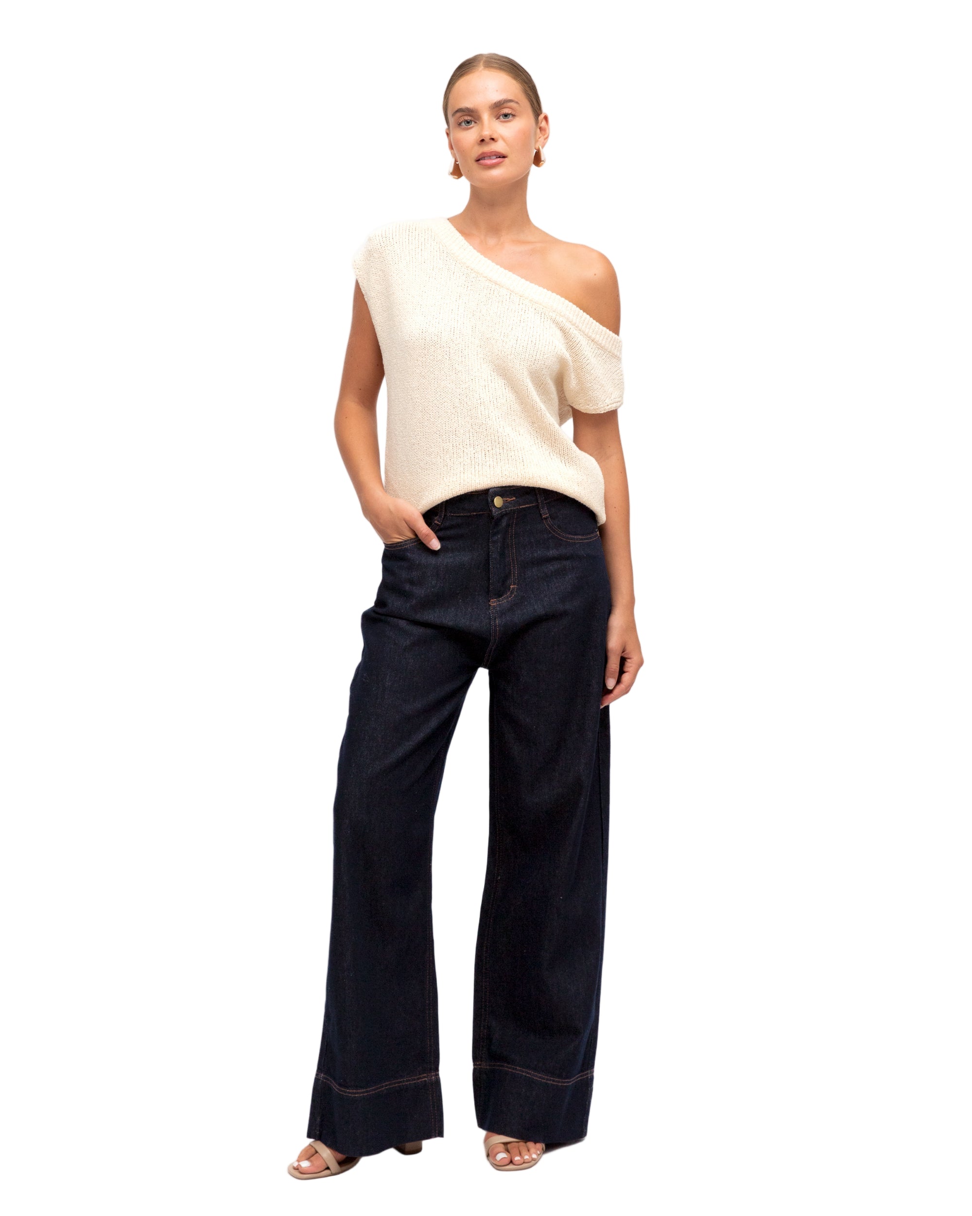 Woman wearing a white sleeveless top and dark blue jeans on a white background