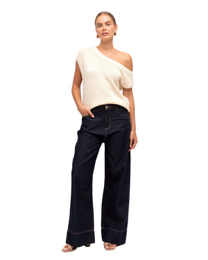 Woman wearing a white sleeveless top and dark blue jeans on a white background
